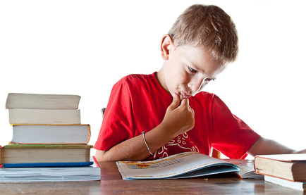 A little boy hard at work on his homework, getting ready to go back to school. Isolated on white background with plenty of copyspace.