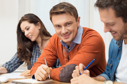 Satisfied Businessman looking at camera with other workers sitting at meeting table