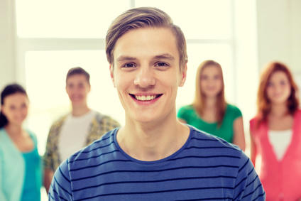 education and school concept - group of smiling students with teenage boy in front