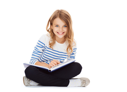 education and school concept - little student girl sitting on floor and reading book