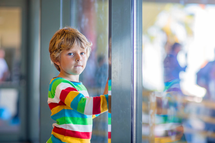 Cute little tired kid boy at the airport, traveling. Upset child waiting near window and looking at plane. Canceled flight due to pilot strike.